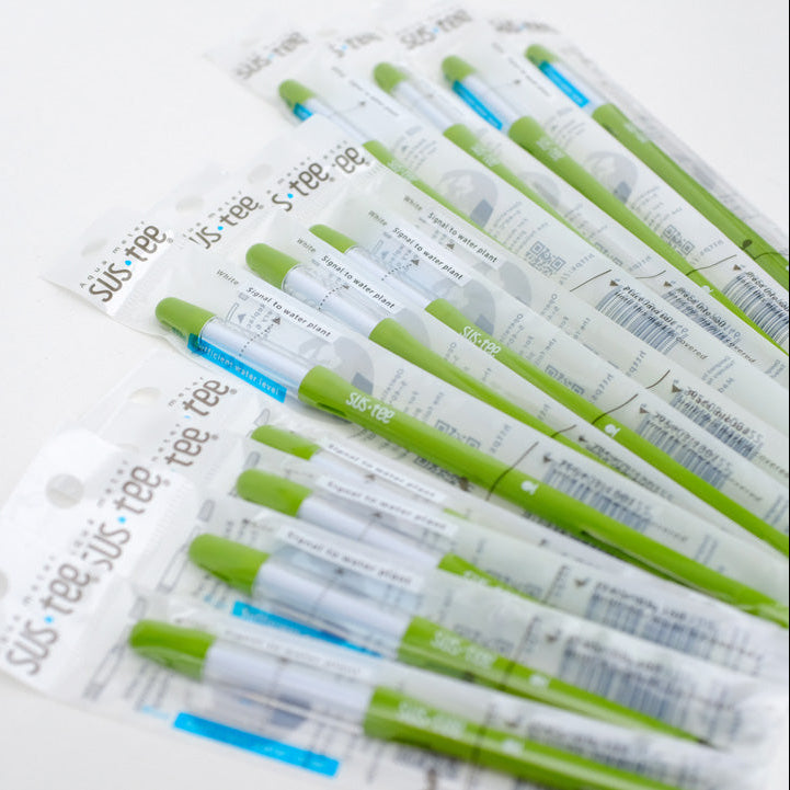 Individually wrapped Sustee watering measuring sticks in white and green colors, laid out on a white surface.